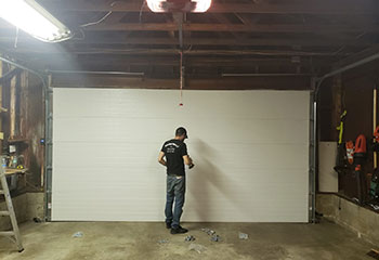 Garage door technician assembling new sectional electric door inside Cypress residential garage